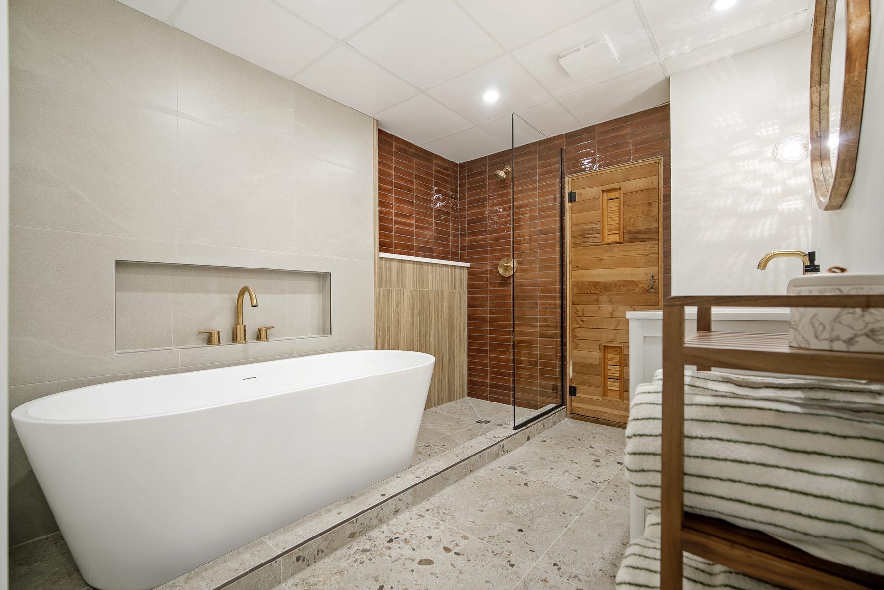 Goldbar spa-inspired basement bathroom — freestanding soaker tub and cedar sauna