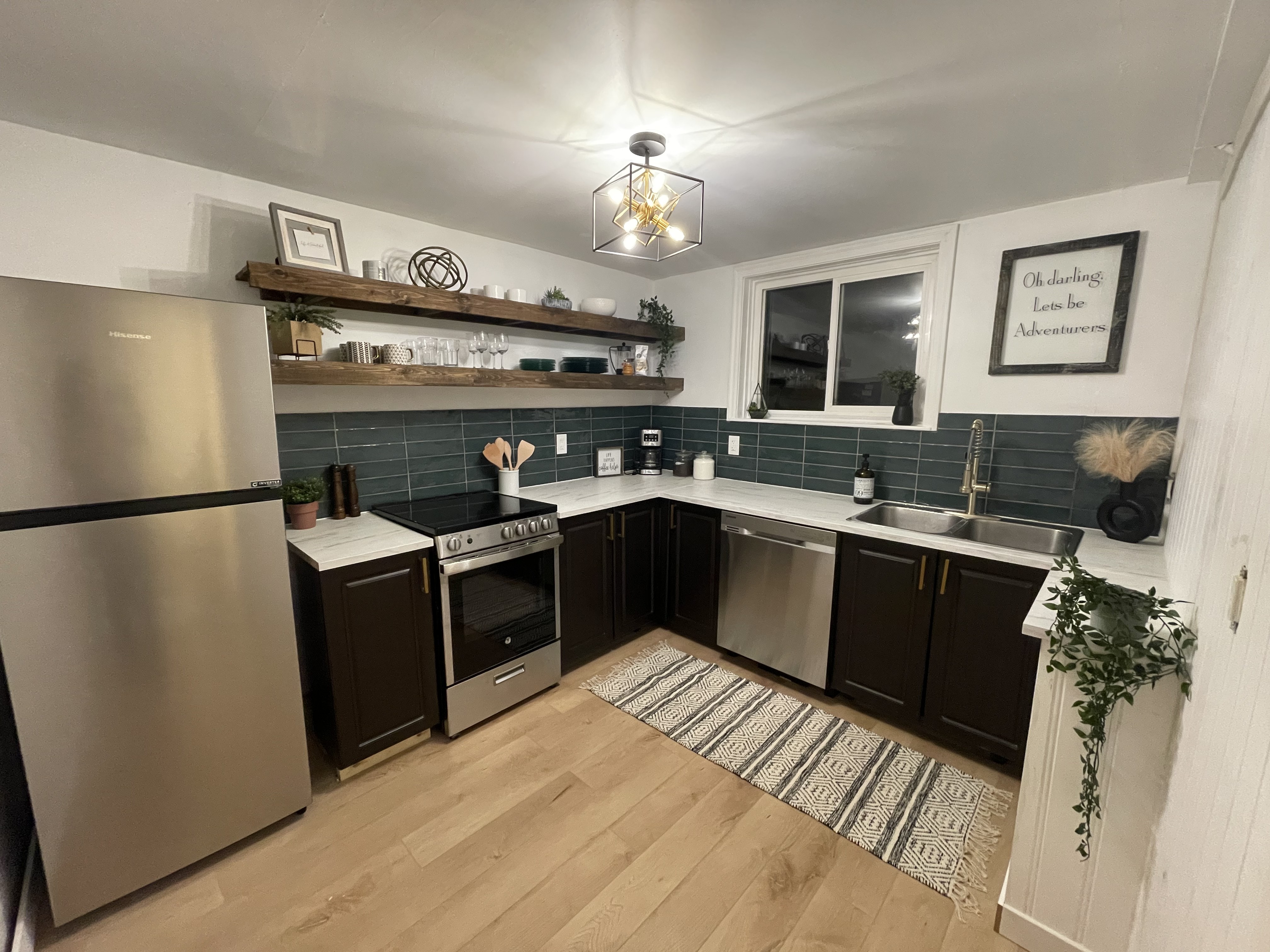 Hazel kitchen — dark cabinets, teal subway tile, floating shelves